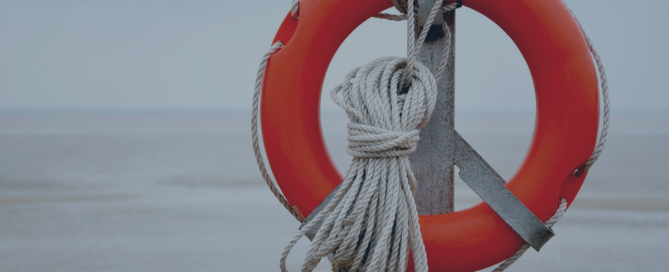 Advice for line managers: image depicts an orange life ring with rope wrapped around it in focus, with the sea in the distance behind out of focus.